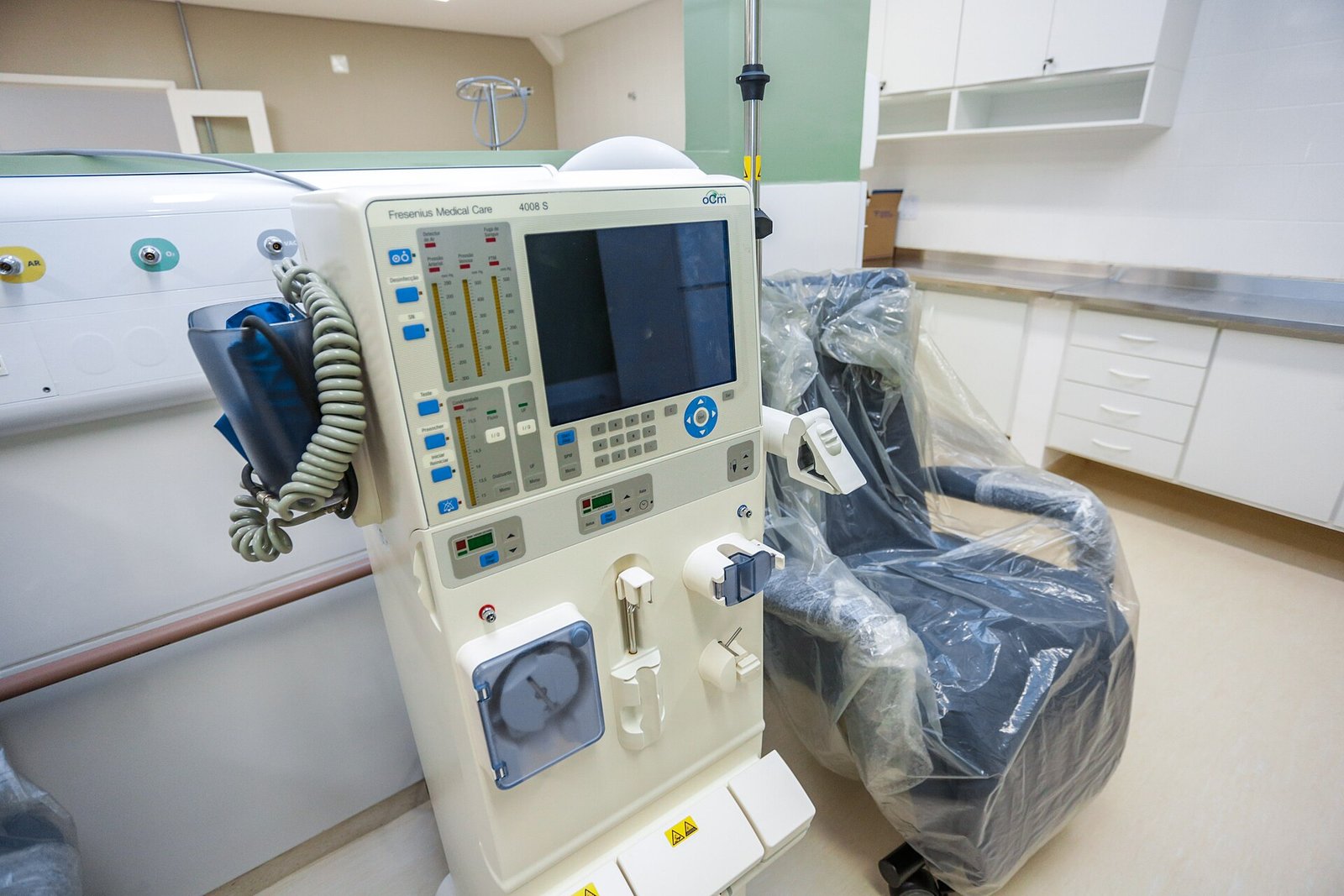 Máquina de hemodiálise ao lado de poltrona em sala de centro de tratamento renal