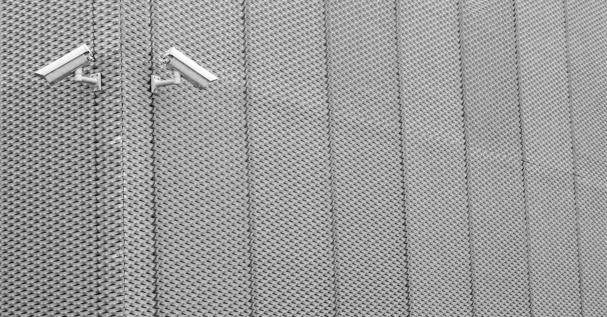 Duas câmeras de vigilância instaladas em parede metálica de fachada
