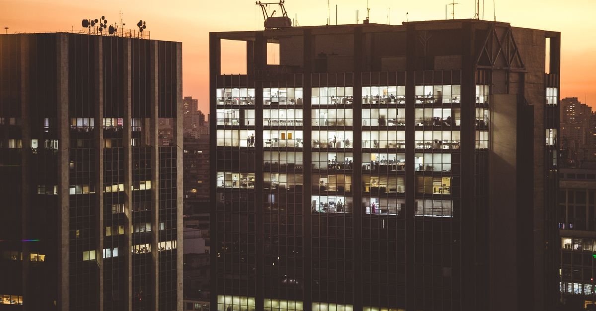 Prédios de escritórios iluminados ao entardecer em região central de grande cidade