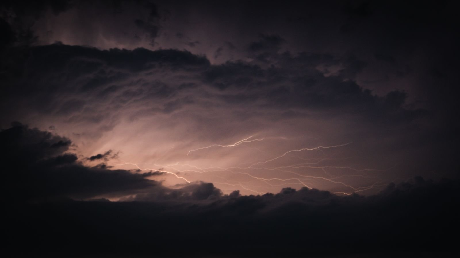 Raios riscam o céu escuro entre nuvens carregadas durante uma tempestade noturna