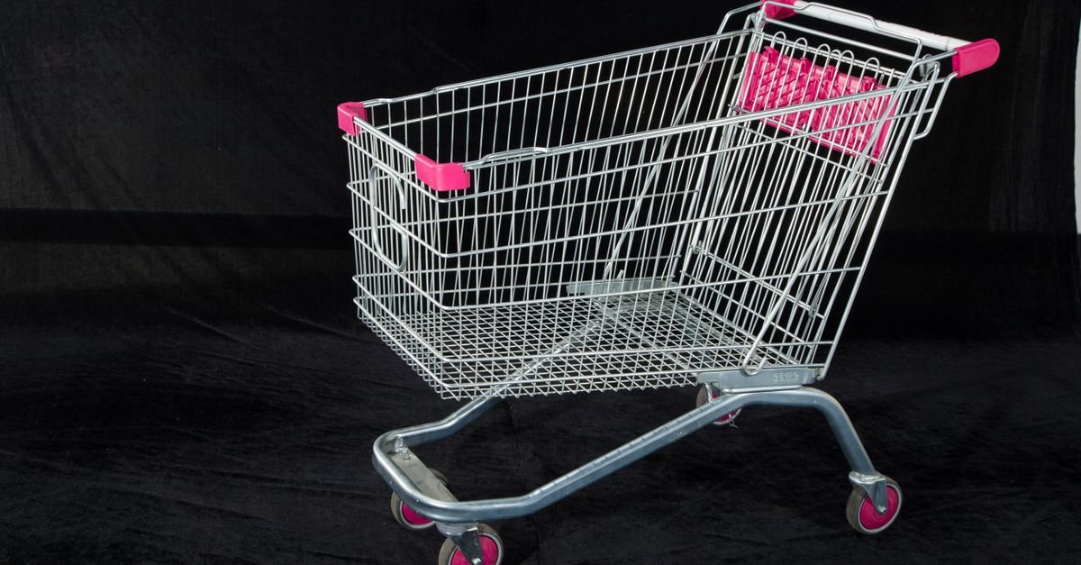 Carrinho de supermercado metálico com detalhes cor-de-rosa sobre fundo escuro