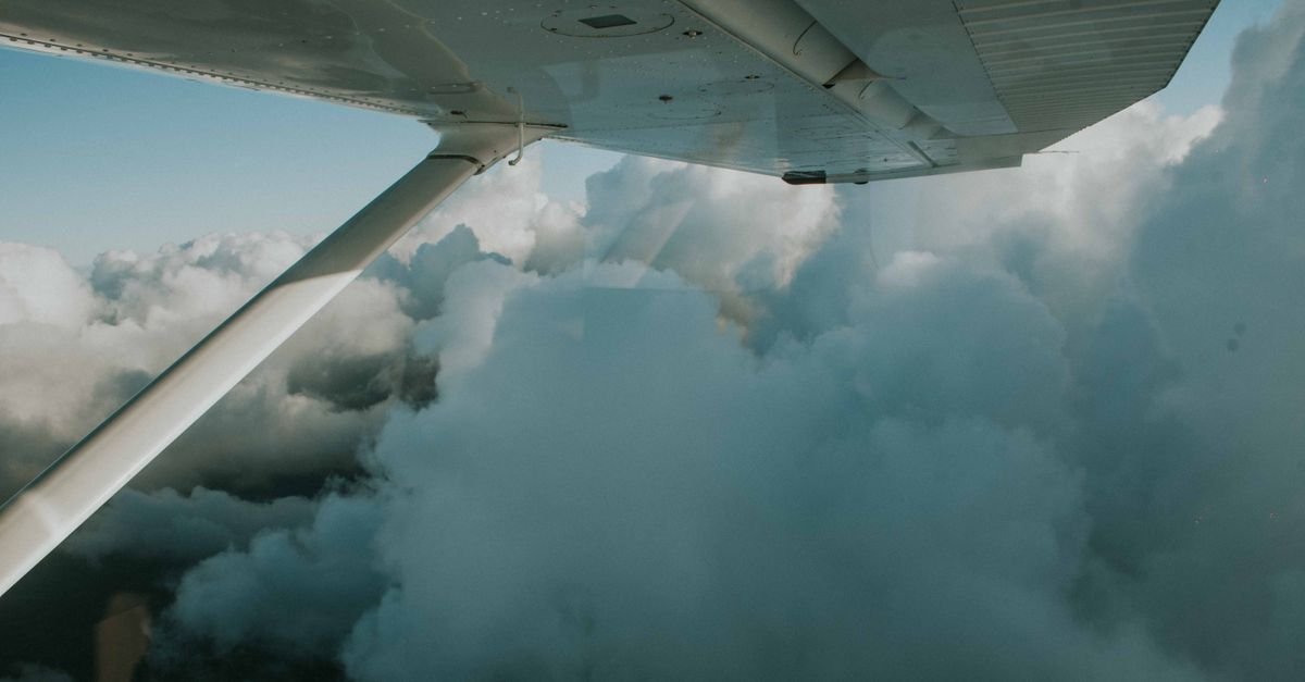 Asa de avião em voo acima de nuvens densas