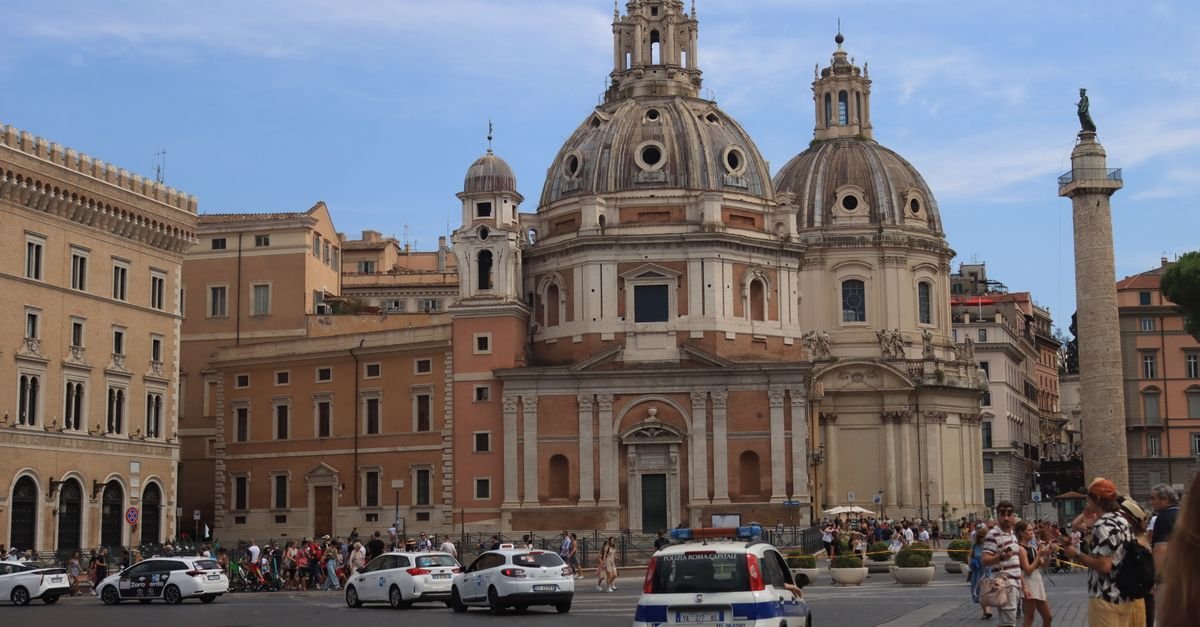 Praça em Roma com a Coluna de Trajano e igrejas de cúpula ao fundo em dia de sol forte