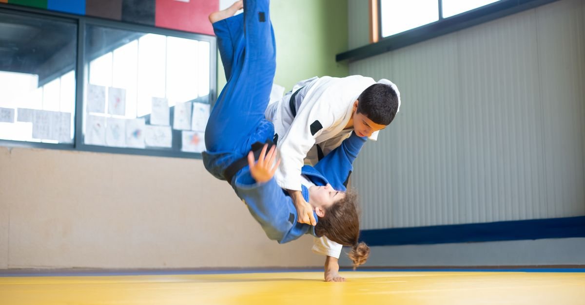 Judocas de quimono azul e branco durante projeção em tatame