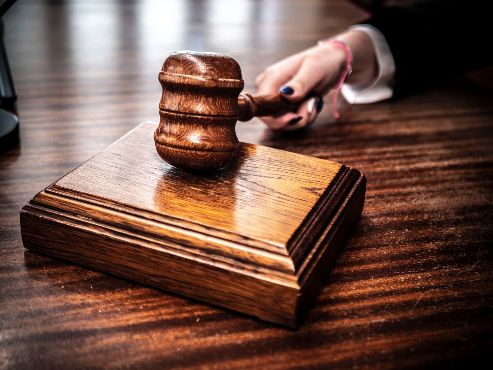 Martelo de madeira sobre base de madeira em uma mesa de tribunal, em foto ilustrativa