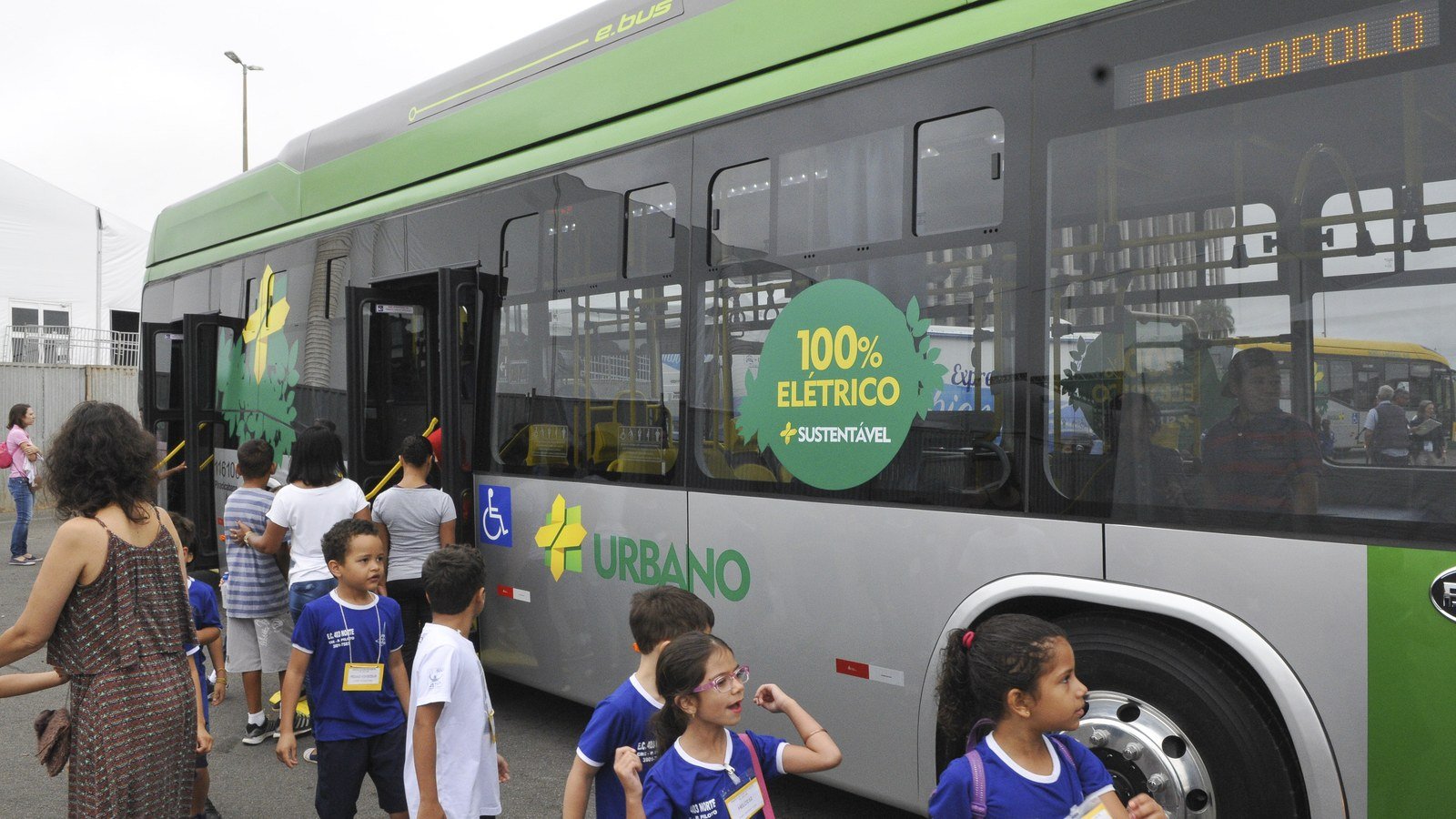 Ônibus elétrico da frota de Brasília, com a faixa 100% elétrico, e estudantes embarcando