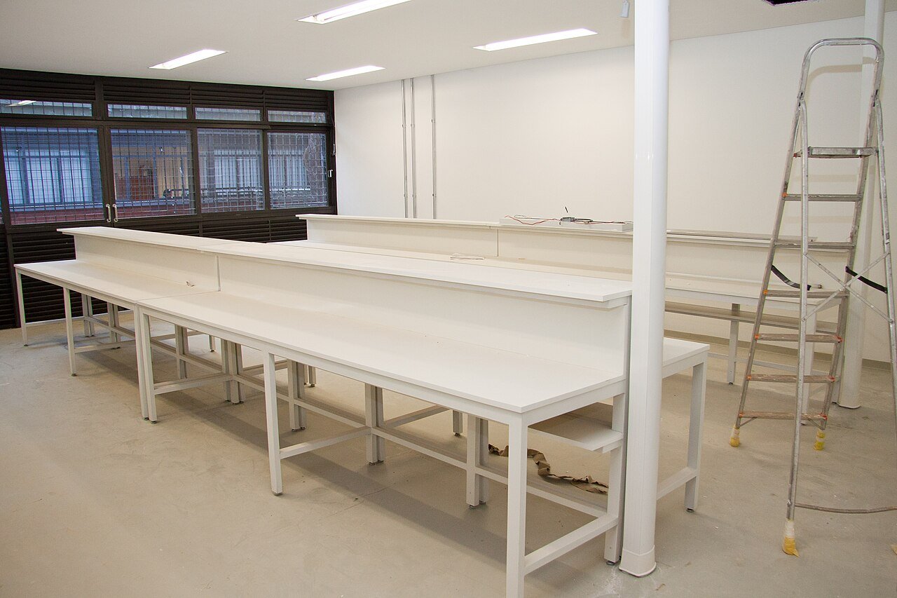 Bancadas brancas de um laboratório em obras na Universidade de Brasília, com escada ao fundo