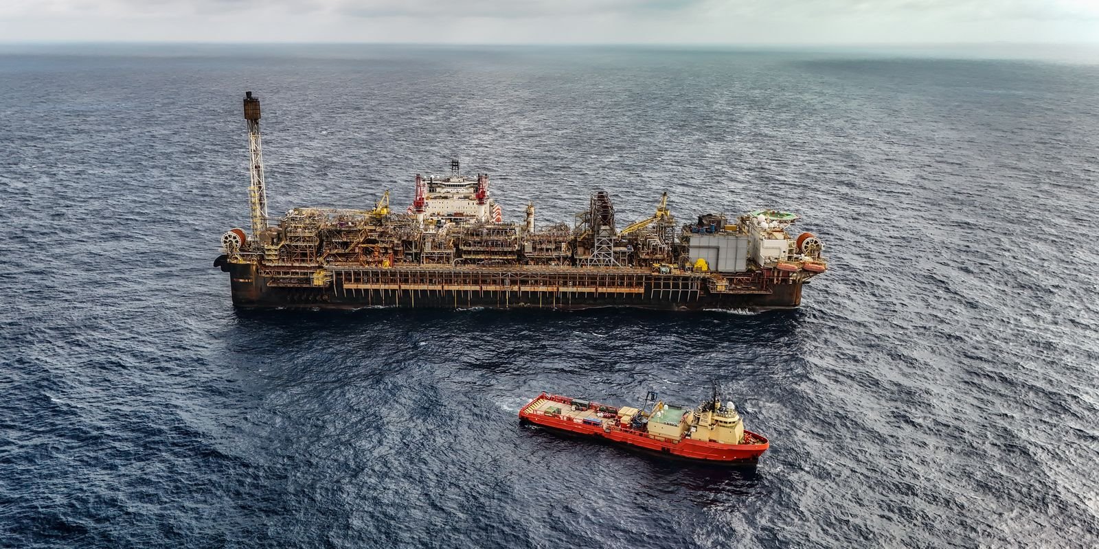 Plataforma de produção de petróleo em alto-mar com embarcação de apoio ao lado