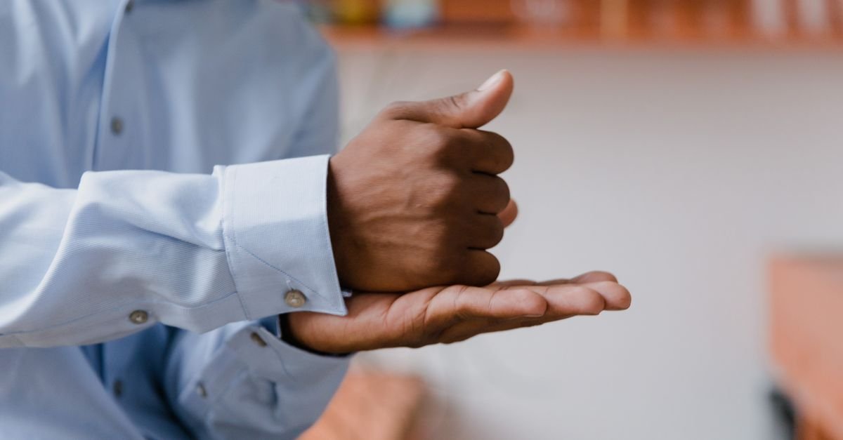Mãos de uma pessoa fazendo um sinal em língua de sinais