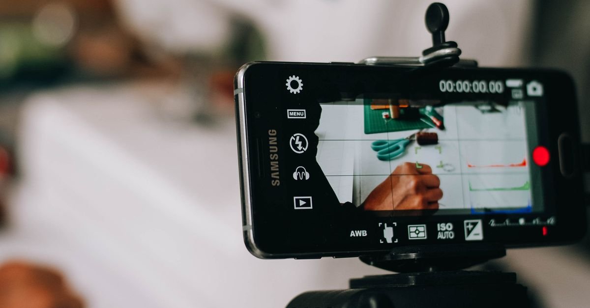 Celular preso a um tripé gravando vídeo, com a tela mostrando o enquadramento da cena