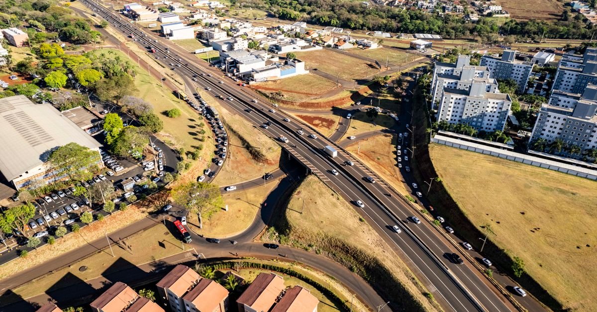 Vista aérea de rodovia com pista central, vias marginais e viaduto de acesso