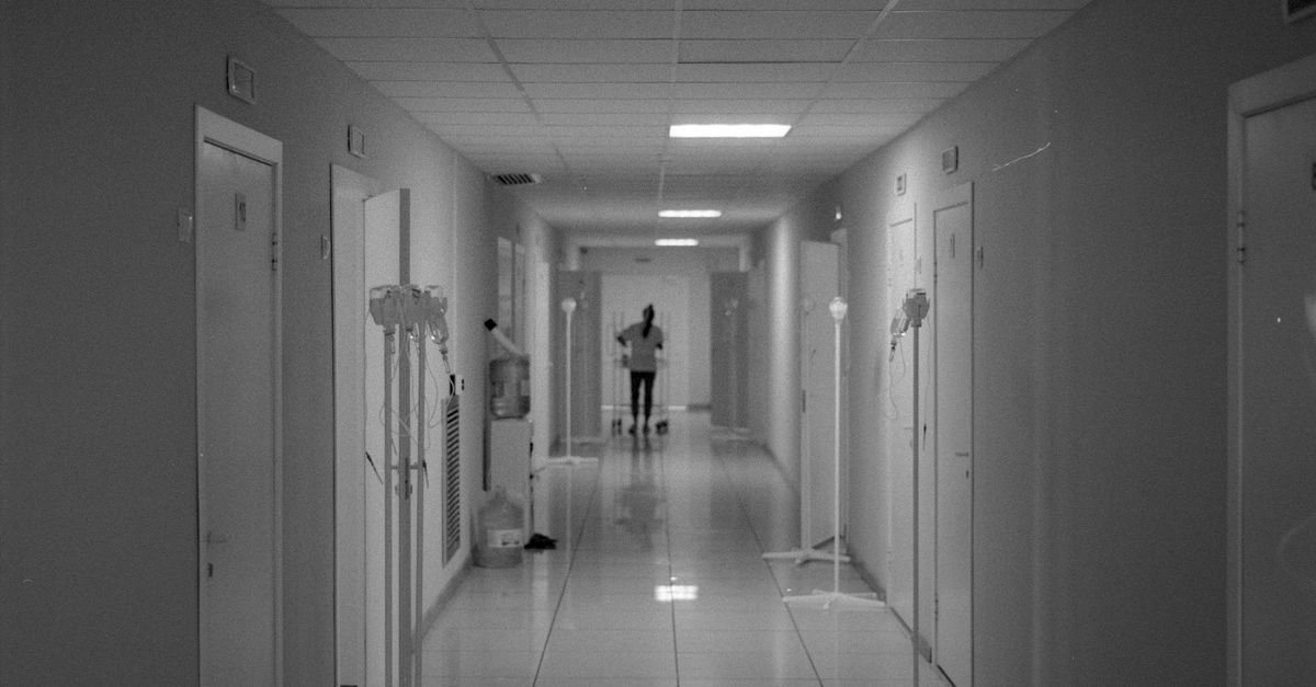 Corredor de hospital em preto e branco com profissional de saúde ao fundo