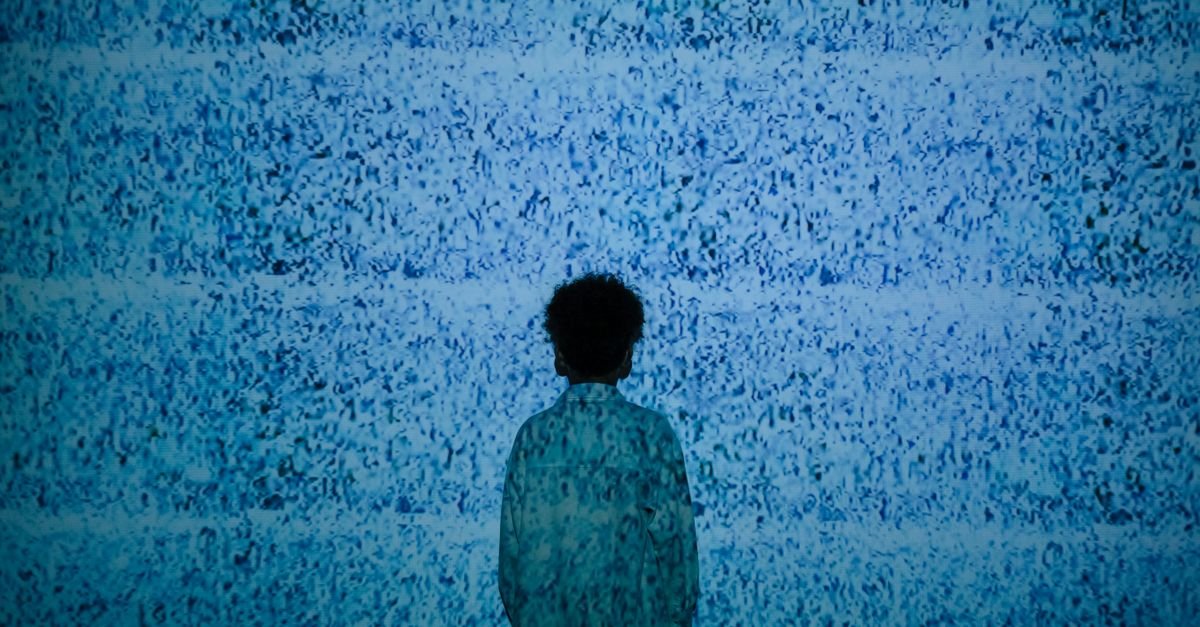 Criança de costas diante de tela com chuvisco, em imagem conceitual sobre uso de telas