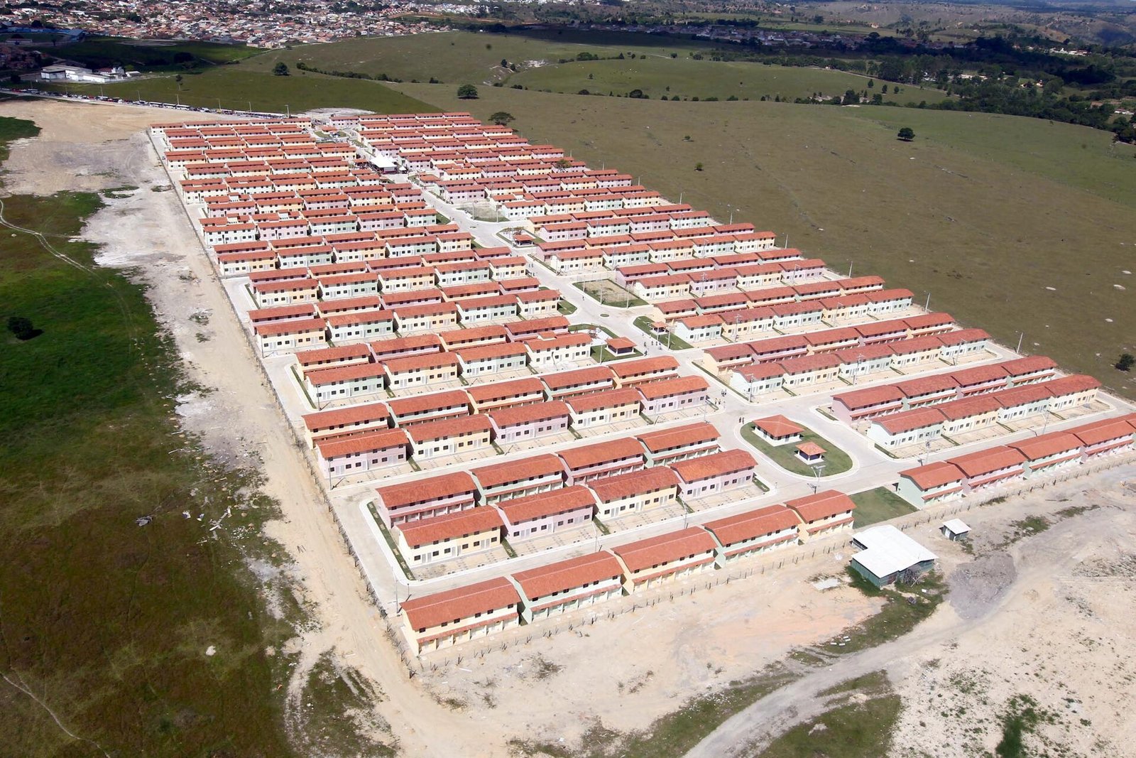 Vista aérea de conjunto habitacional do programa Minha Casa, Minha Vida com centenas de casas em fileiras, em Eunápolis, na Bahia