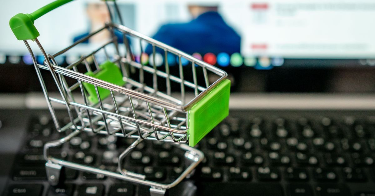 Carrinho de compras em miniatura sobre teclado de notebook, representando compras internacionais pela internet