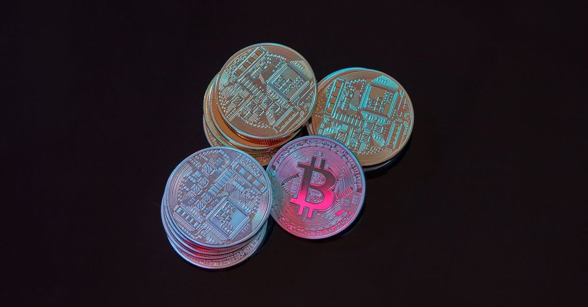 Pilhas de moedas metálicas de bitcoin sobre fundo escuro com iluminação azul e rosa