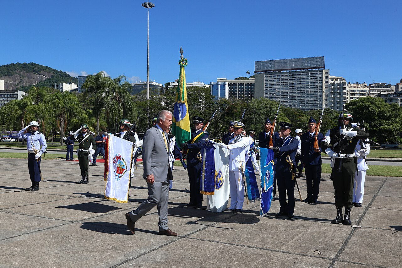 Ministro da Defesa, José Múcio Monteiro, caminha diante de tropa em formatura militar com a bandeira do Brasil ao fundo