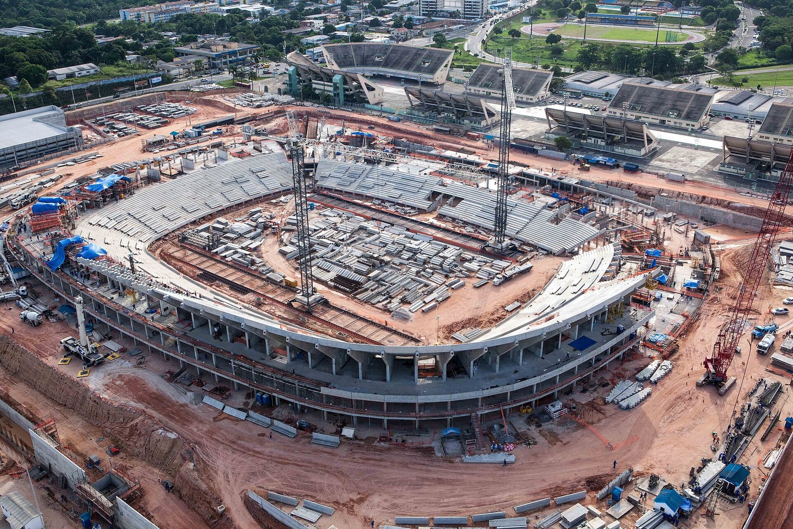 Vista aérea de obra pública de grande porte em fase de construção, com gruas e estruturas de concreto