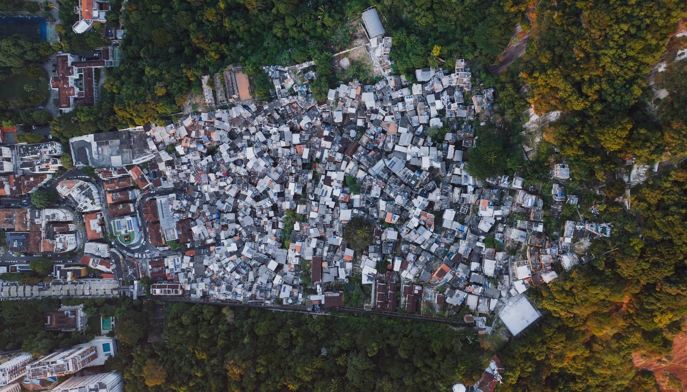 Vista aérea de comunidade densamente construída ao lado de área arborizada