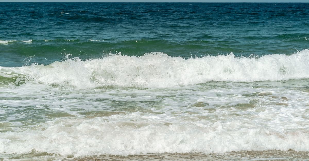 Onda quebrando na areia da praia em dia de sol
