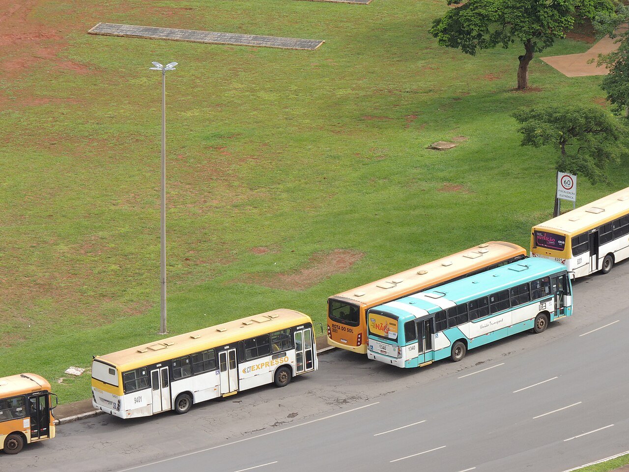 Ônibus do transporte público coletivo parados junto ao meio-fio em via de Brasília