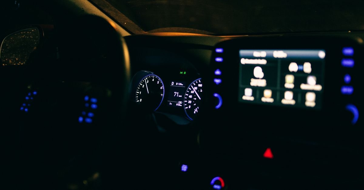 Painel iluminado de um carro visto de dentro do veículo durante a noite