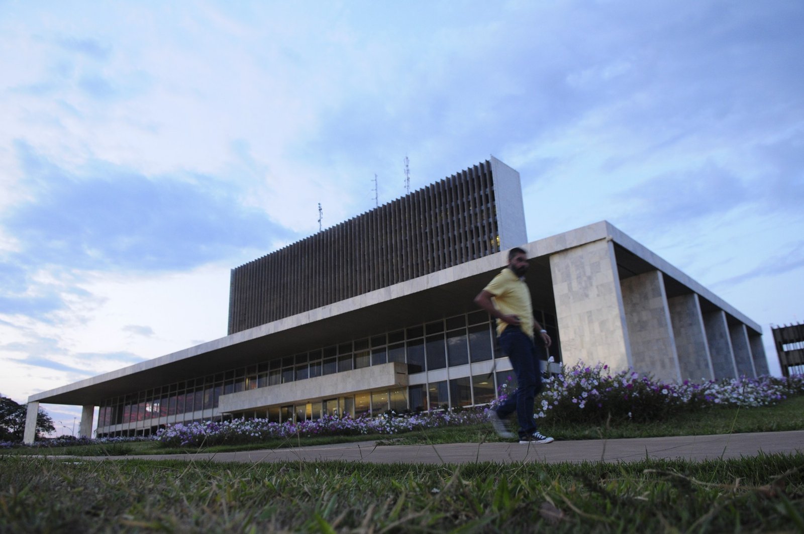 Fachada do Palácio do Buriti, sede do governo do Distrito Federal, ao entardecer, com um pedestre desfocado em primeiro plano