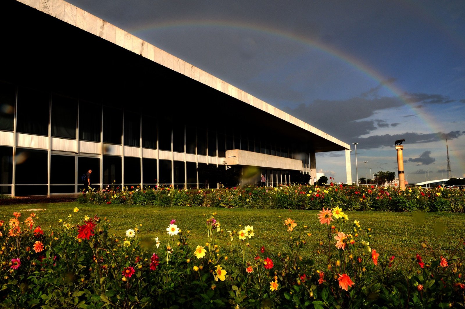 Fachada lateral do Palácio do Buriti com arco-íris e canteiro de flores em primeiro plano, em foto de arquivo