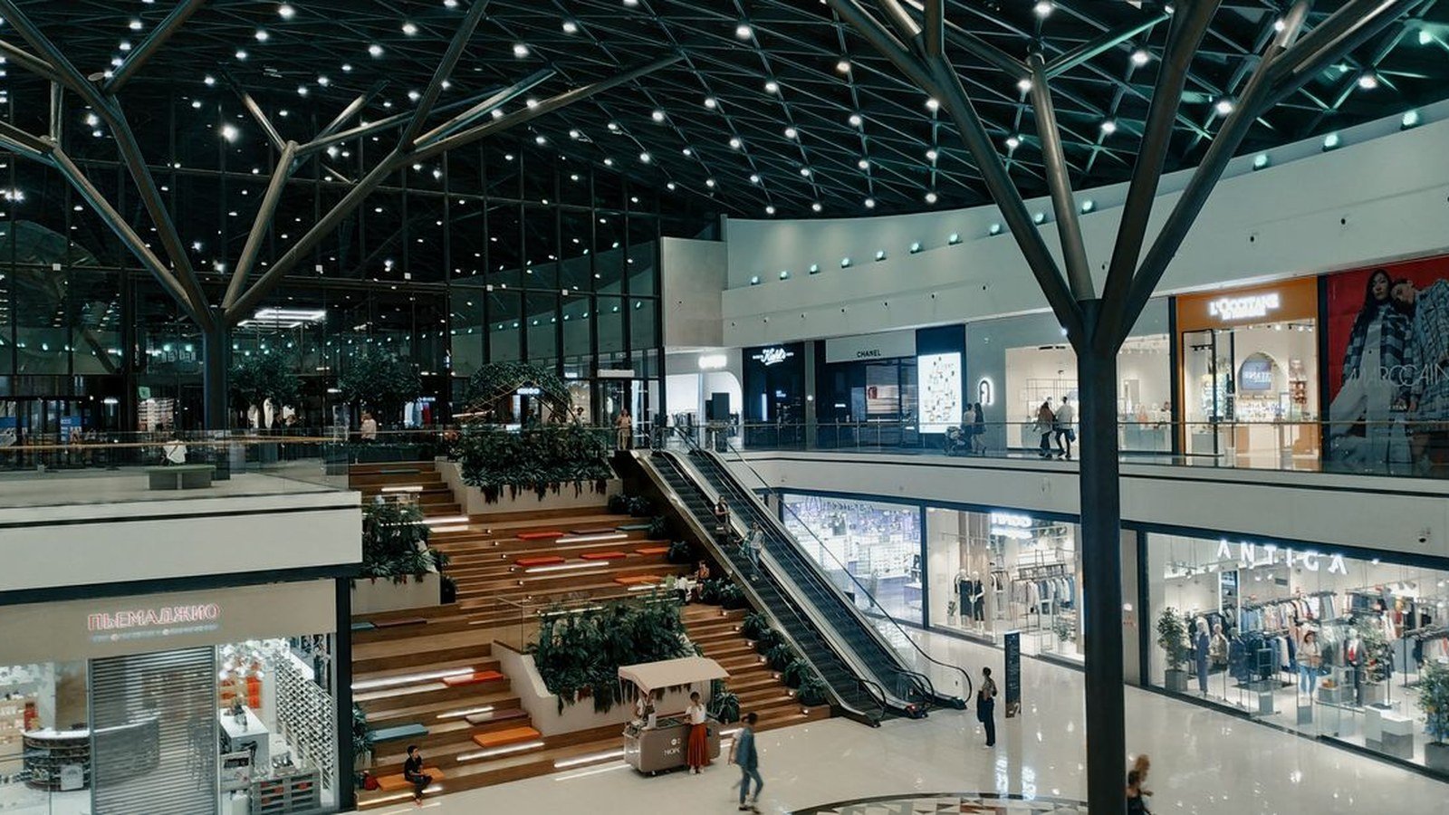 Corredor de um shopping contemporâneo com lojas, plantas e iluminação natural