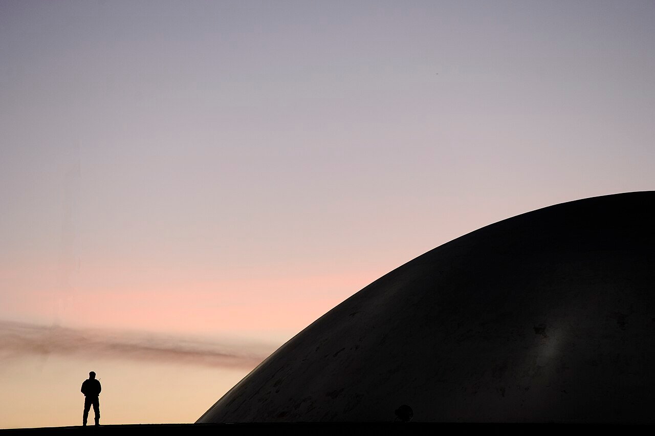 Cúpula do Senado Federal ao entardecer, em Brasília, com a silhueta de uma pessoa em primeiro plano