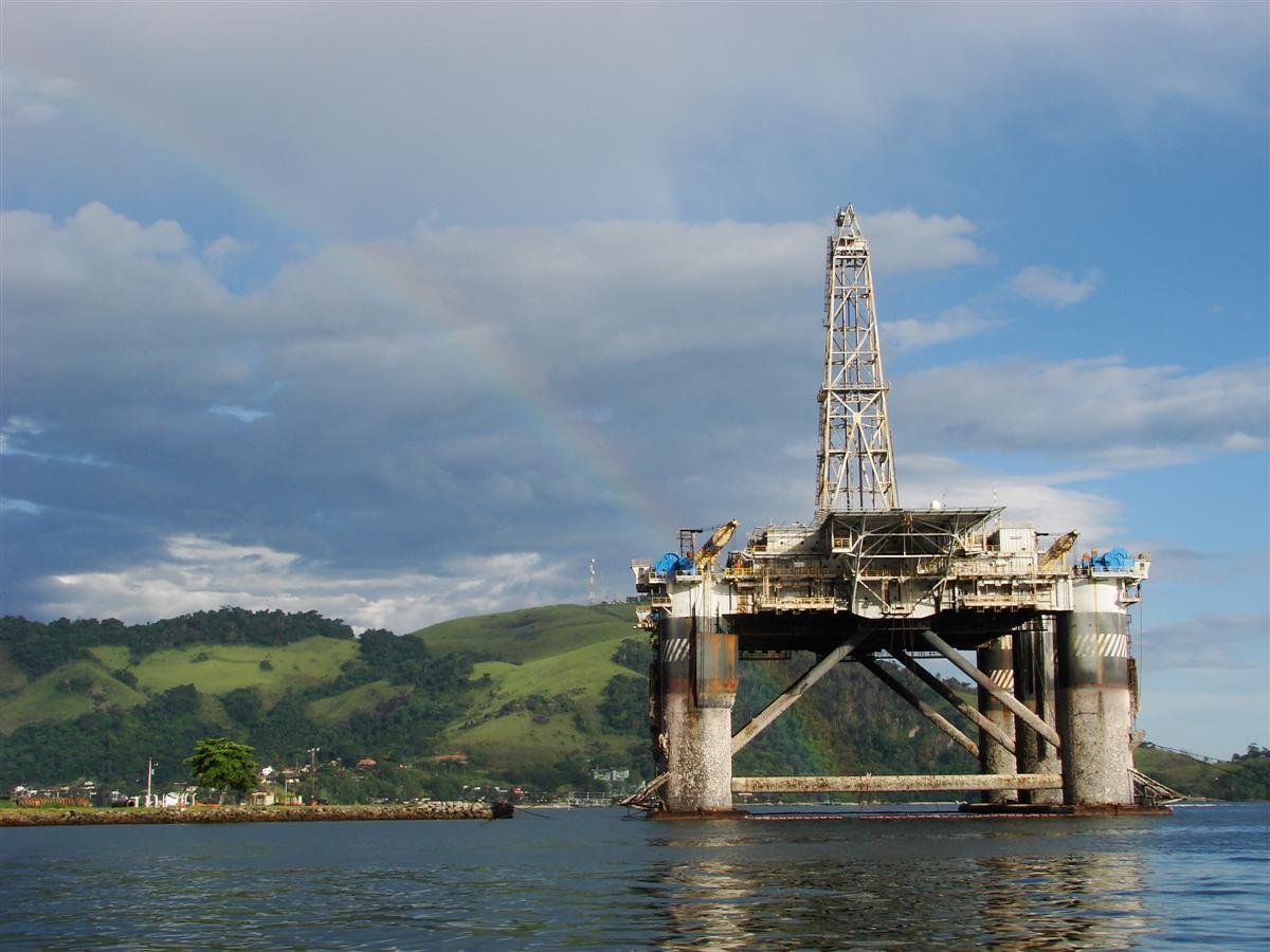 Plataforma de petróleo ancorada em baía no litoral brasileiro, com morros ao fundo