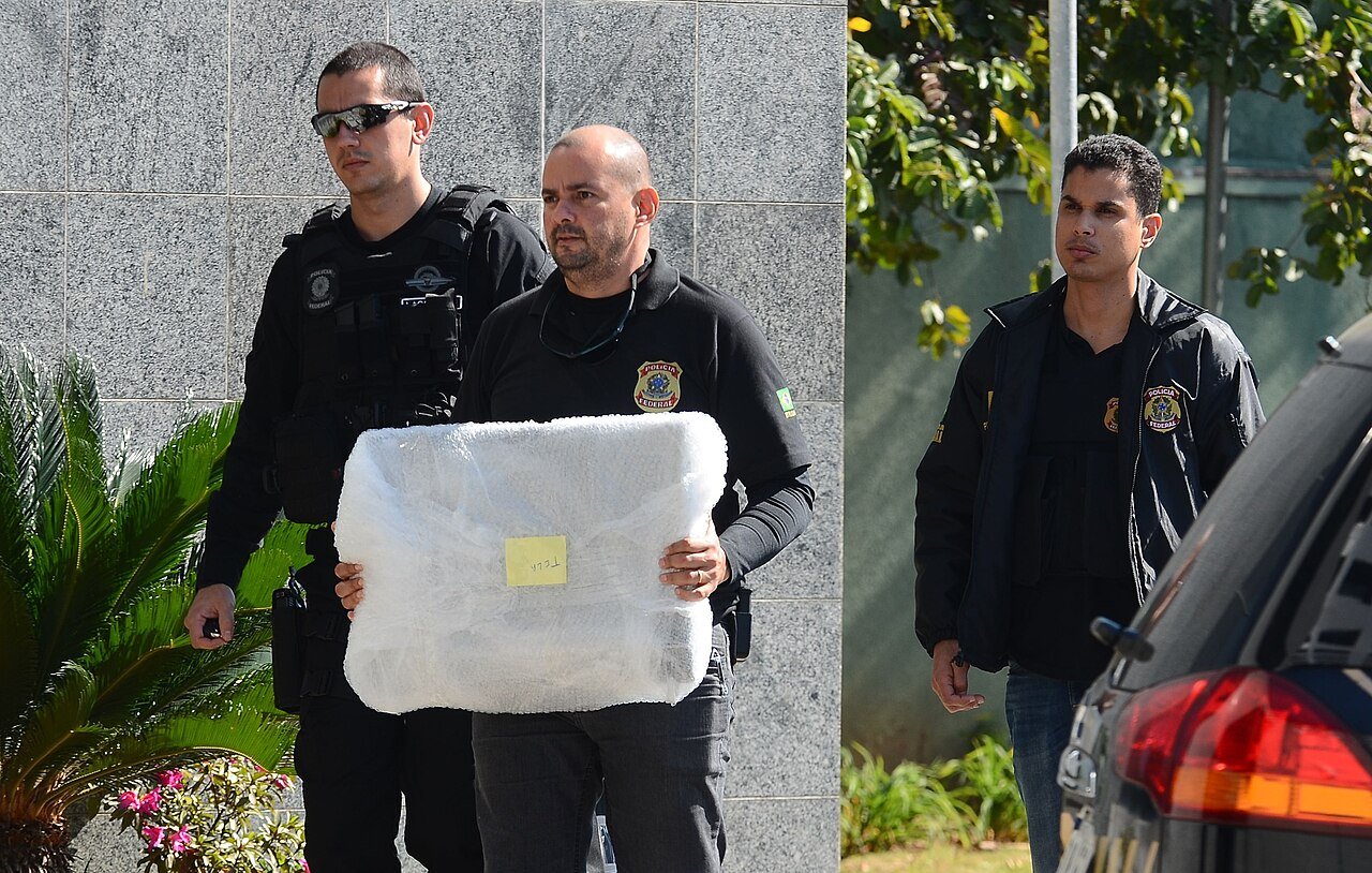 Agentes da Polícia Federal carregam material apreendido durante operação