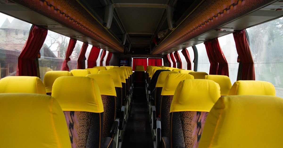 Corredor central e poltronas vazias no interior de um ônibus rodoviário