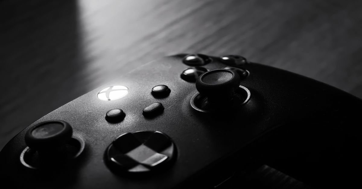 Close em preto e branco de um controle de videogame sobre superfície de madeira