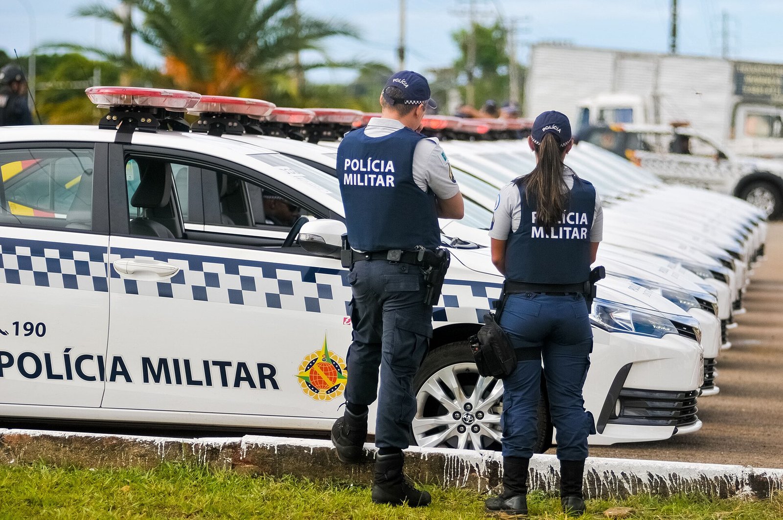 Policiais militares do Distrito Federal ao lado de viaturas com o brasão do DF