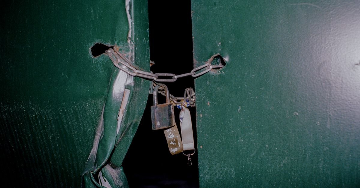 Portas metálicas verdes fechadas com corrente e dois cadeados
