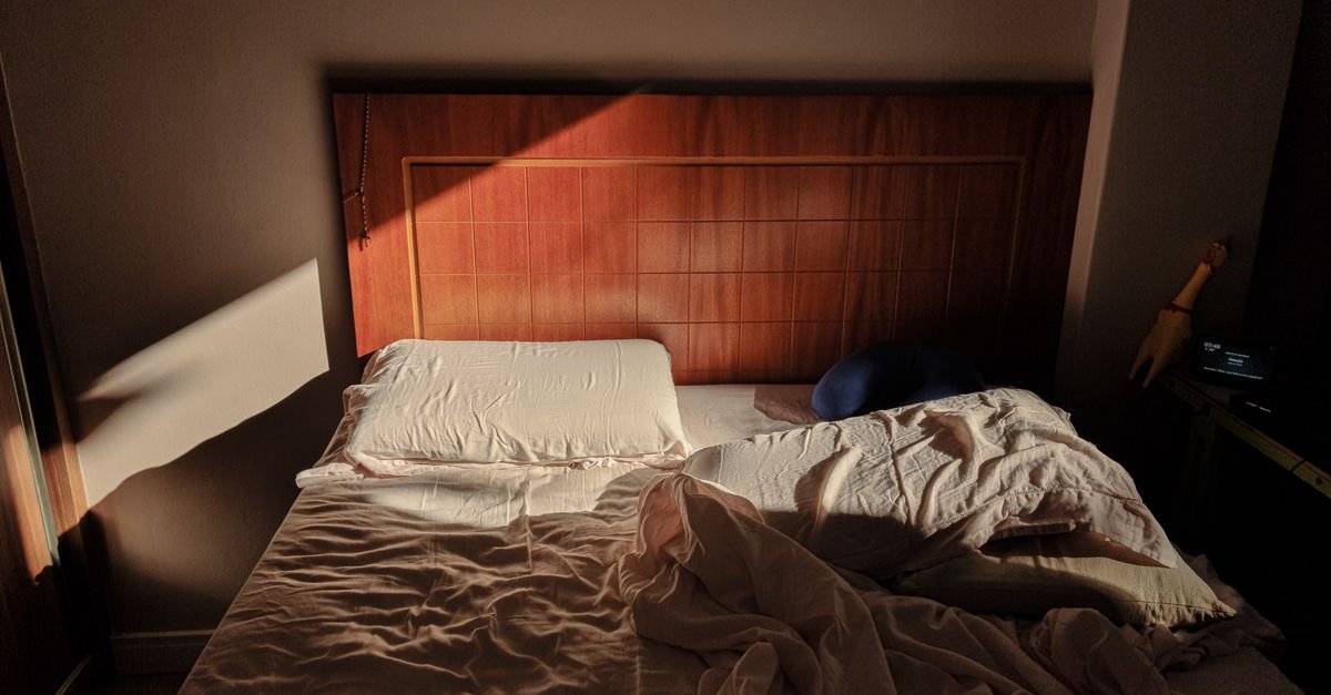 Cama desarrumada em quarto iluminado pela luz da janela
