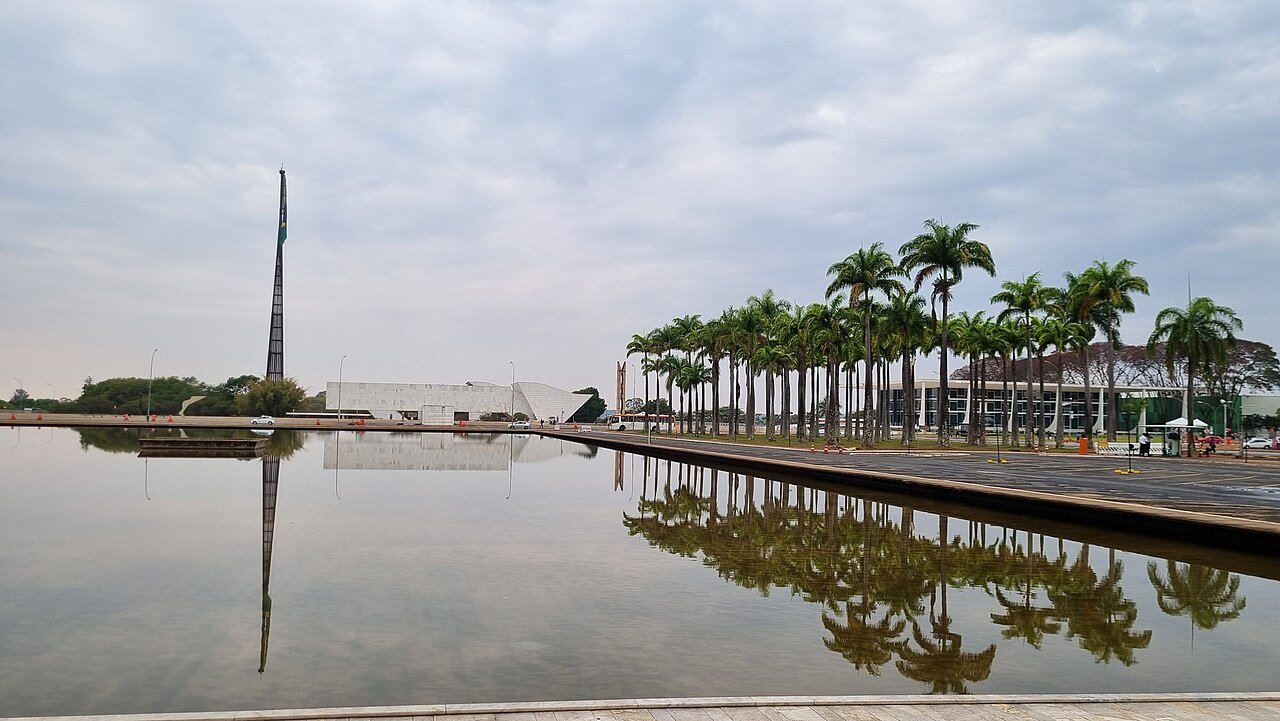 Praça dos Três Poderes, em Brasília, com mastro da bandeira, palmeiras imperiais e espelho d'água