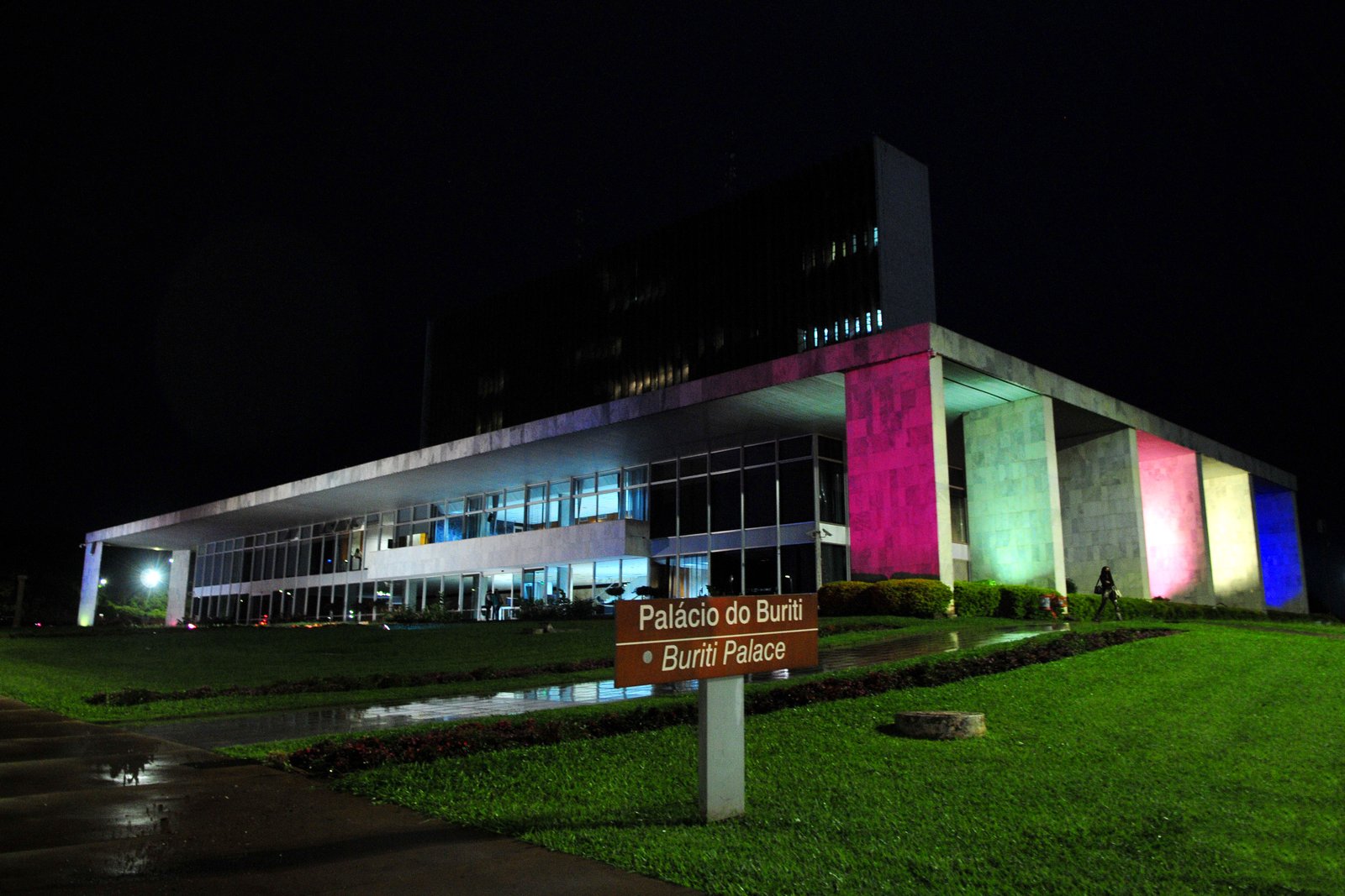 Fachada do Palácio do Buriti iluminada à noite, com placa de identificação em primeiro plano