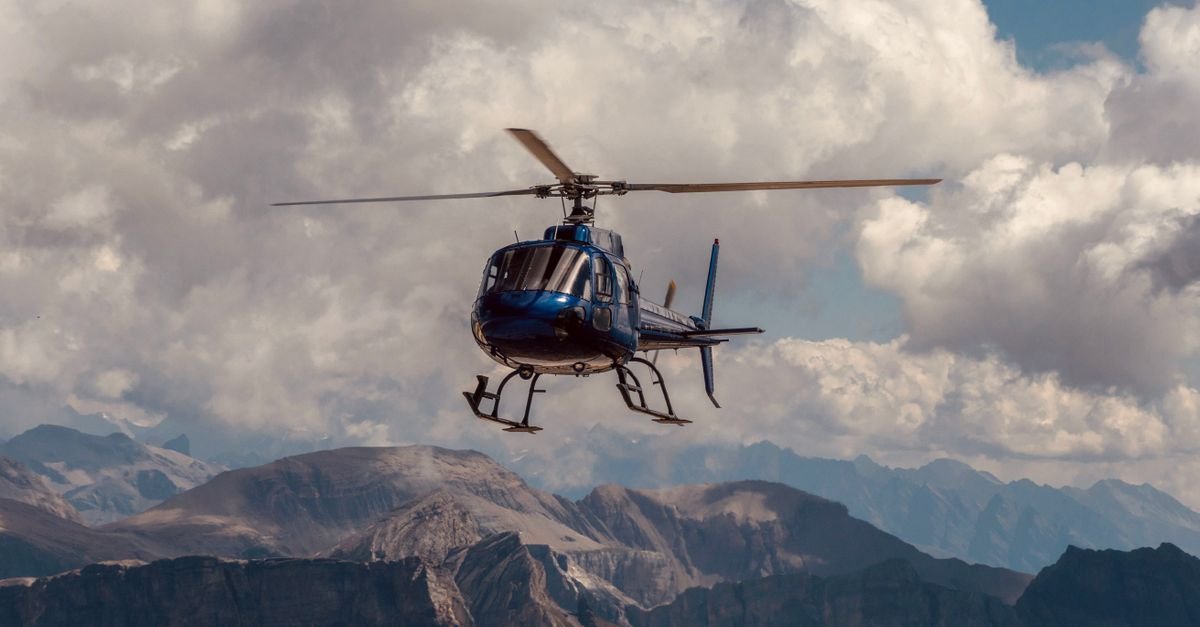 Helicóptero monomotor em voo sobre uma cadeia de montanhas, em imagem ilustrativa