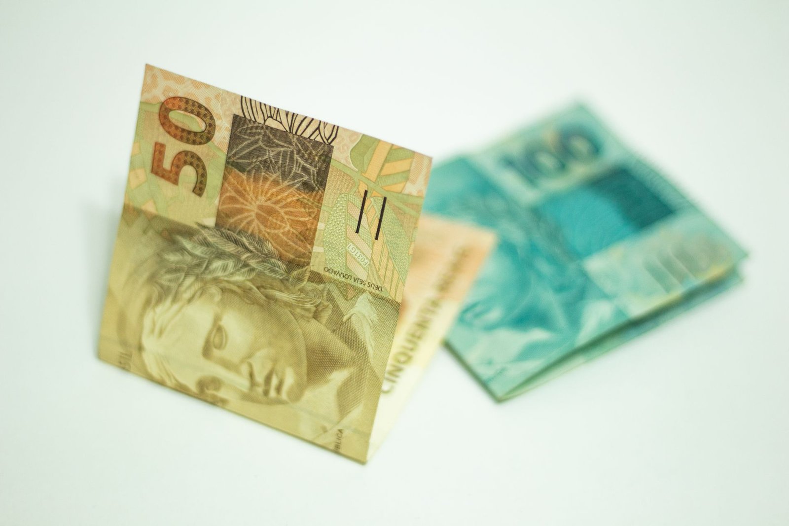 Cédulas de 50 e 100 reais sobre superfície branca