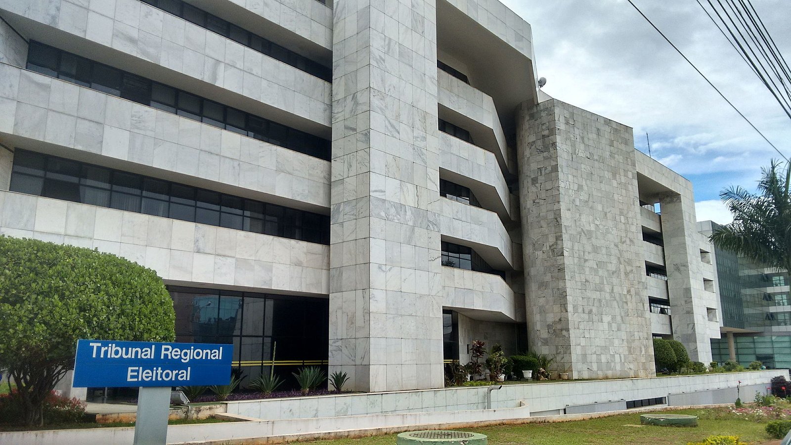 Fachada da sede do Tribunal Regional Eleitoral do Distrito Federal, com placa azul de identificação no jardim