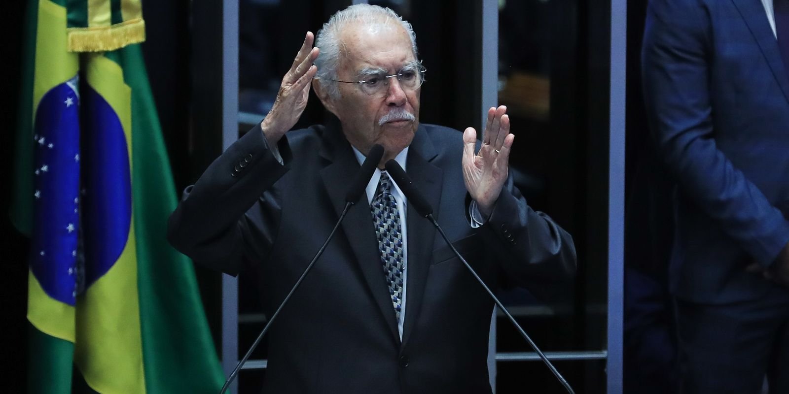 José Sarney gesticula na tribuna do Senado ao lado da bandeira do Brasil