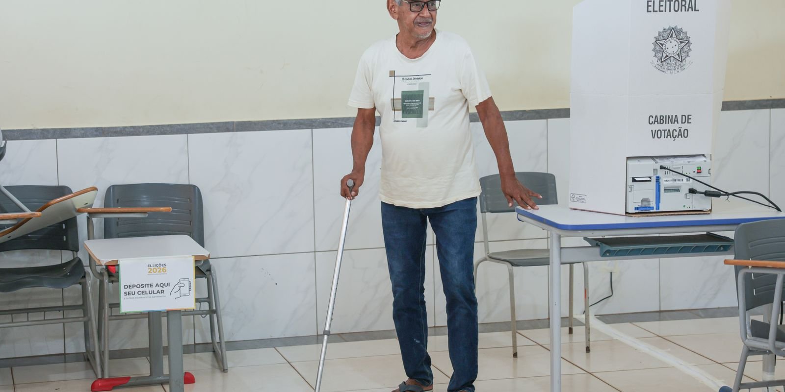 Eleitor com muleta ao lado da cabine de votação, em seção eleitoral, no primeiro turno