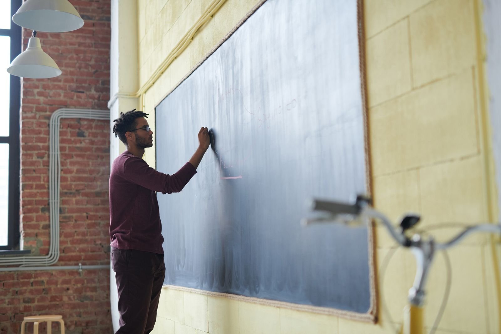Professor escreve com giz em um quadro-negro em sala de aula