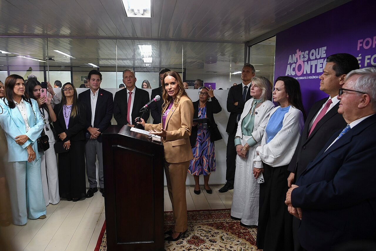 Autoridades reunidas em cerimônia do Senado com painel roxo de campanha de combate à violência contra a mulher