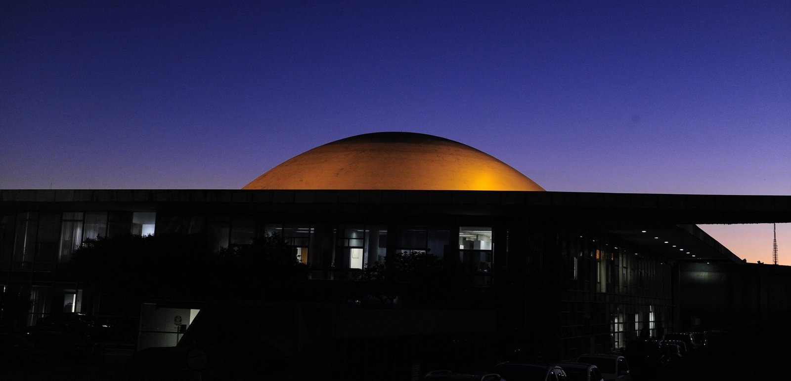 Cúpula do Senado Federal iluminada ao entardecer, em Brasília, com o céu azul-escuro ao fundo