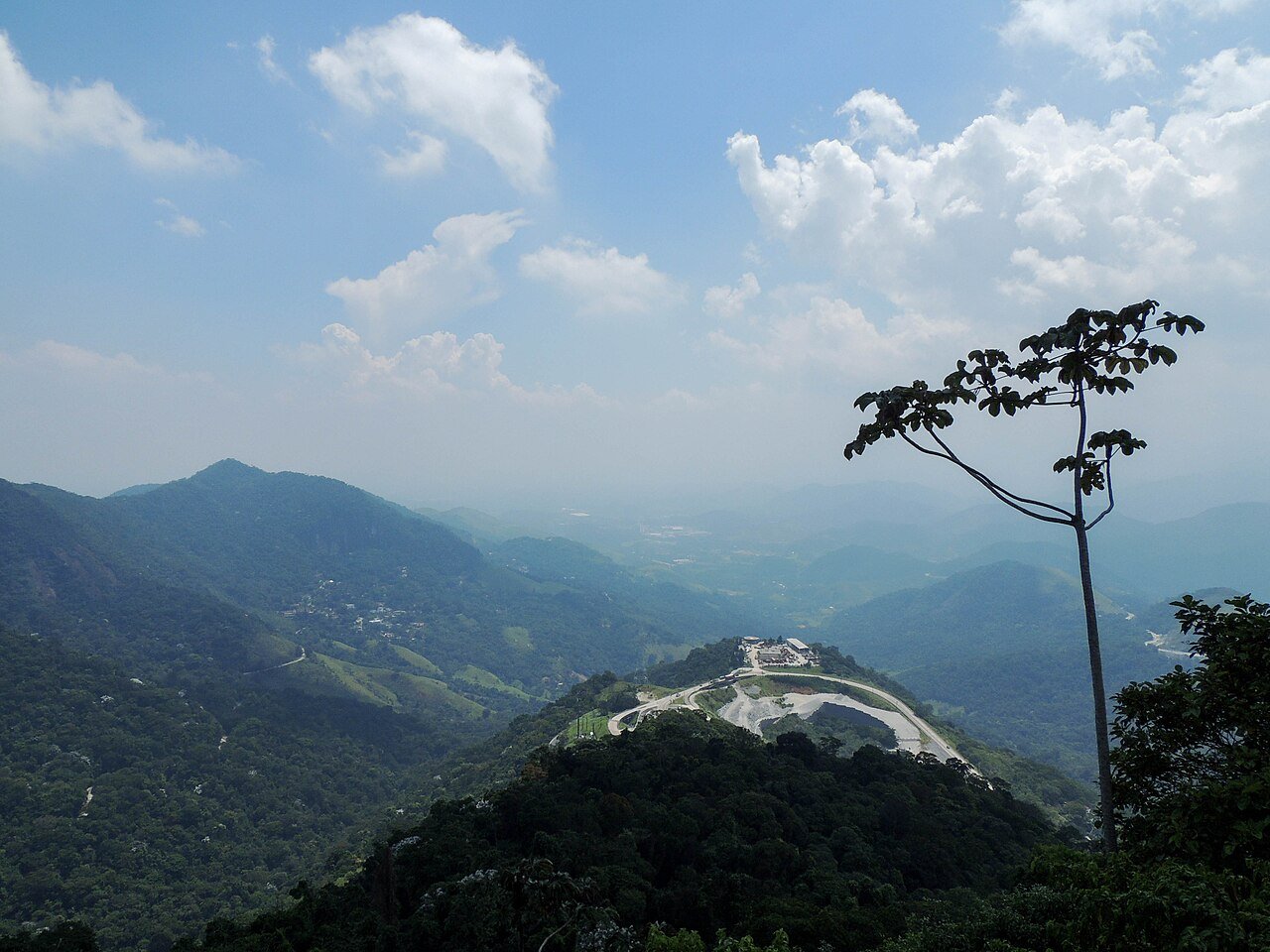 Vista da serra de Petrópolis, na região serrana do Rio de Janeiro, com mata fechada e trecho de estrada ao fundo