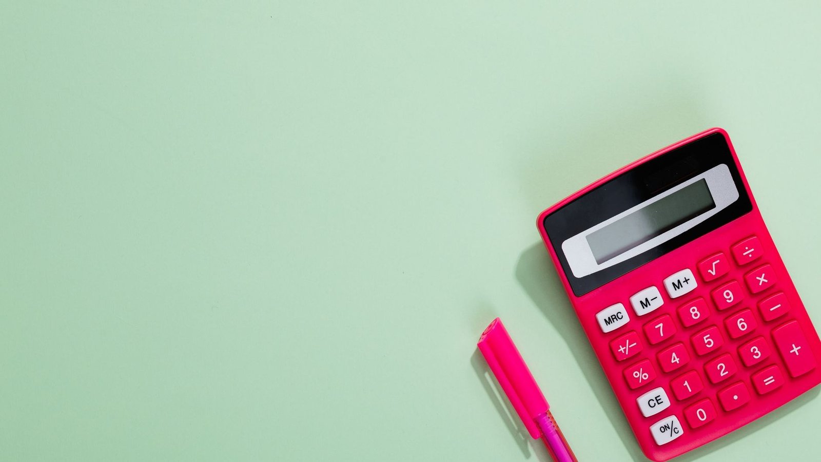 Calculadora e caneta sobre fundo liso, em referência ao cálculo de tributos do microempreendedor individual