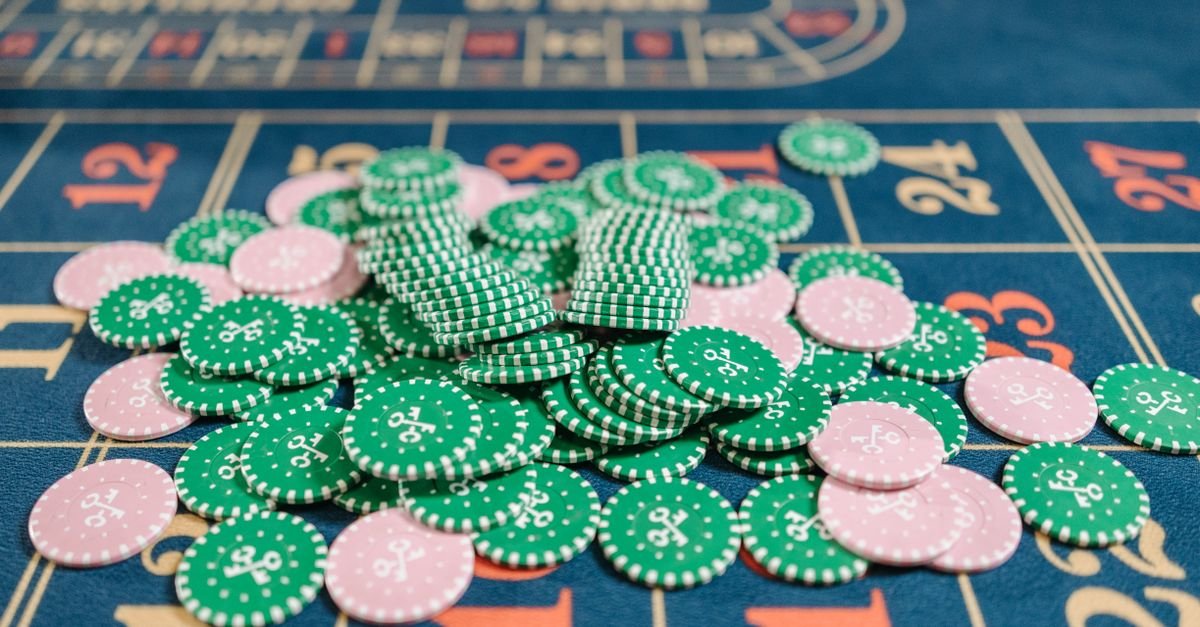 Fichas de cassino verdes e rosas empilhadas sobre mesa de roleta